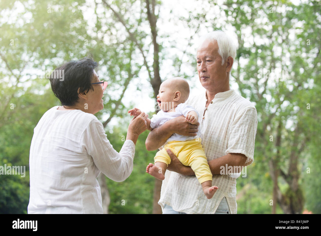 chinese grandfather and grandmother playing with baby grandson at