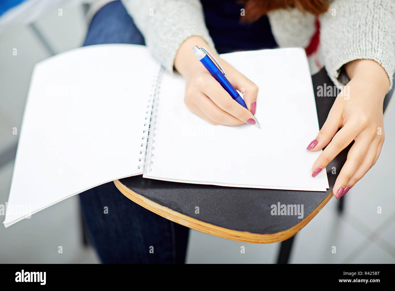 Woman writing in notebook and sitting on student table  Stock Photo
