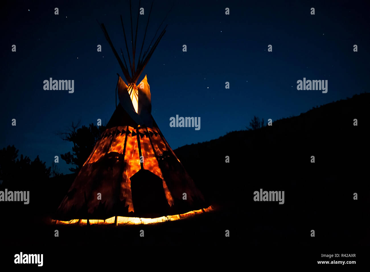 Teepee lit from inside against the starry sky of blue hour Stock Photo