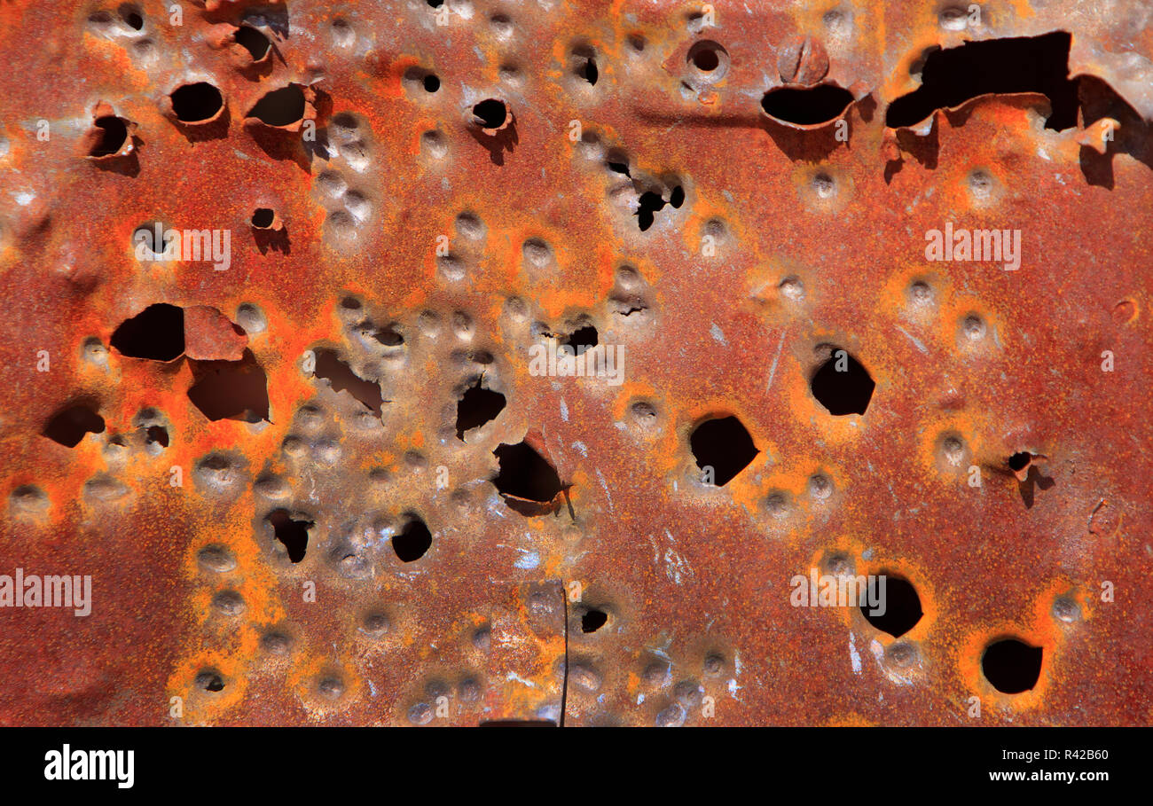 Rusty rustic steel car panel with bullet holes background with copy space. Stock Photo