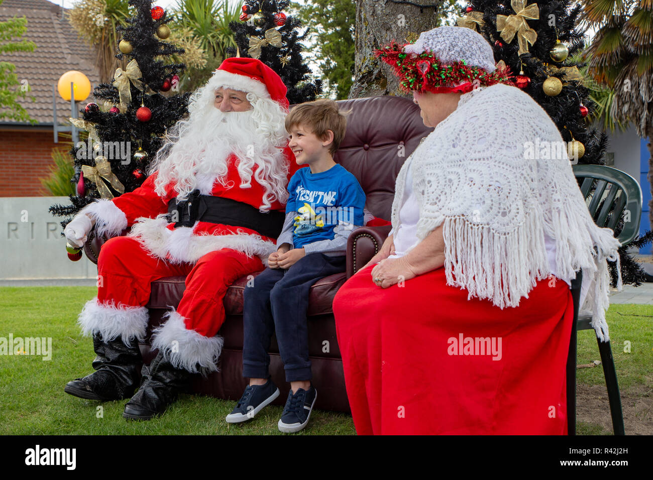 Rangiora, New Zealand - November 23 2018: Father and Mother Christmas listen to a child's Christmas wishes at the Christmas town festival Stock Photo