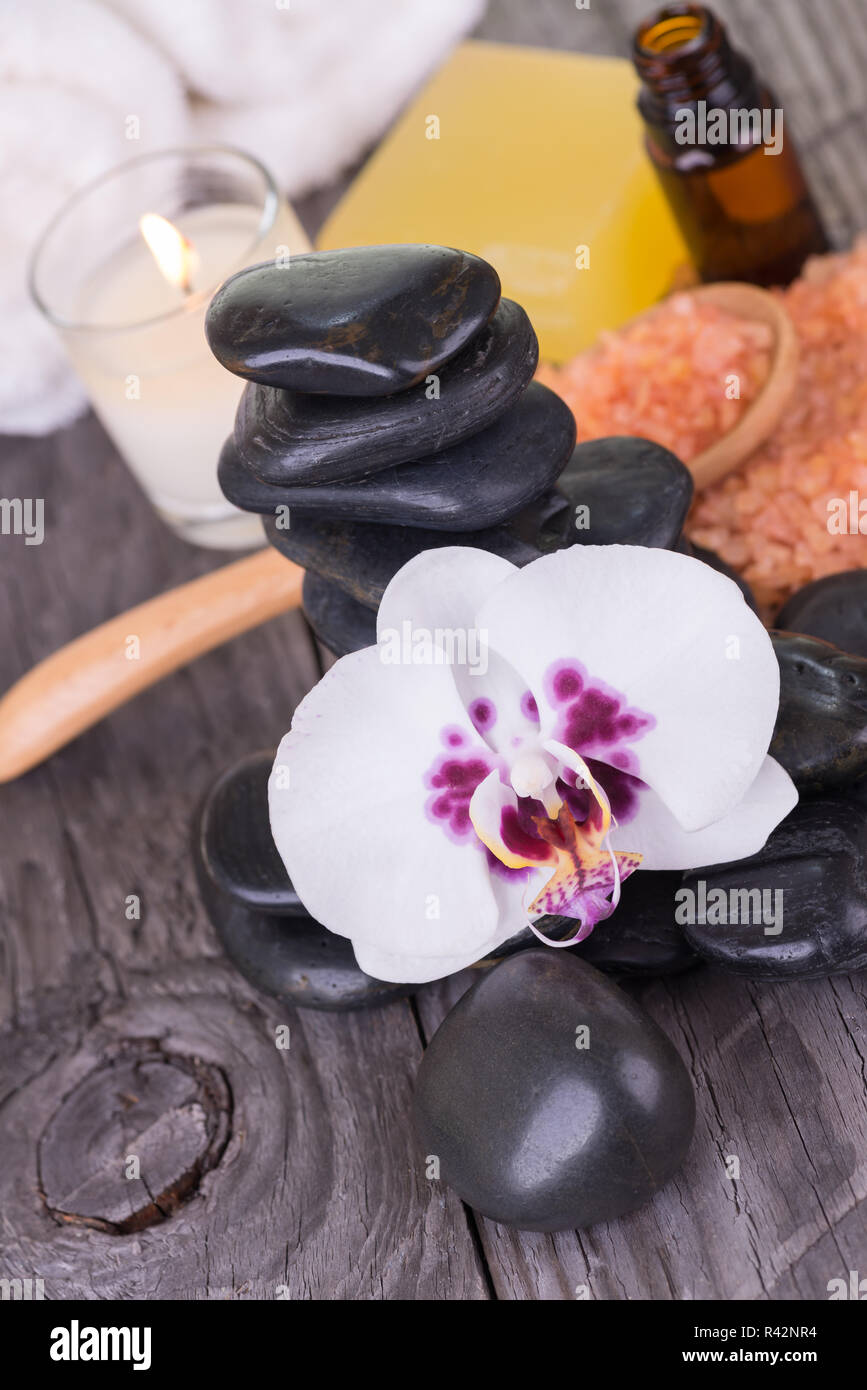 Spa with essential oil, bath salt, loofah, stones and orchid close-up Stock Photo