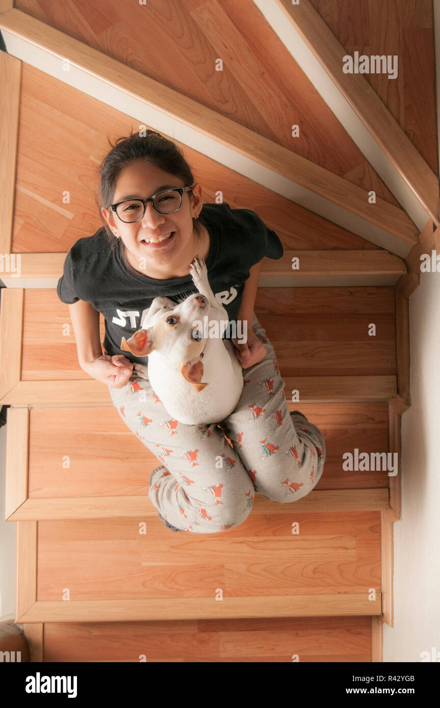 Pets in the home as family member. Teenager seatted on stairs palying with her dog and ready for a portrait photography Stock Photo