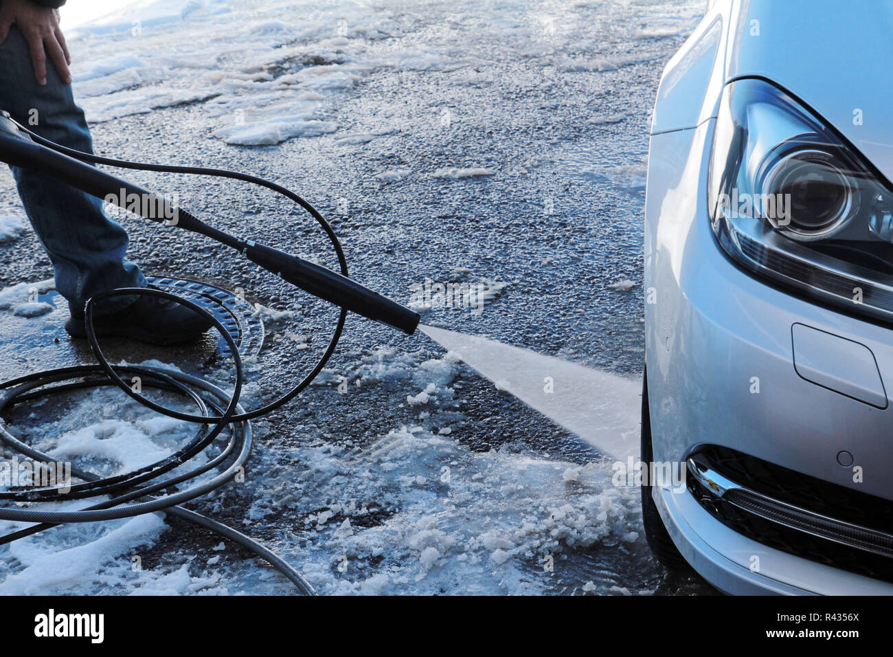 winter car wash - a man washes his car in the winter Stock Photo