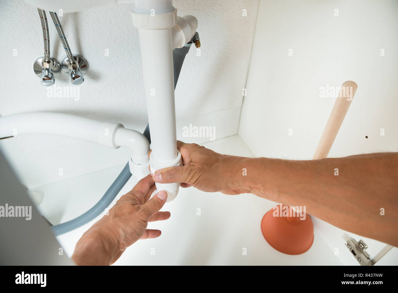 Plumber Working On Pipes Under Kitchen Sink Stock Photo Alamy