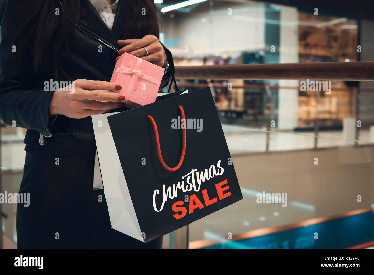 Christmas Shopping. Happy Woman with Shopping Bags in Shopping Mall.Sales. Christmas Gifts.Shopping Mall. woman's hands put a Christmas gift in the package Stock Photo