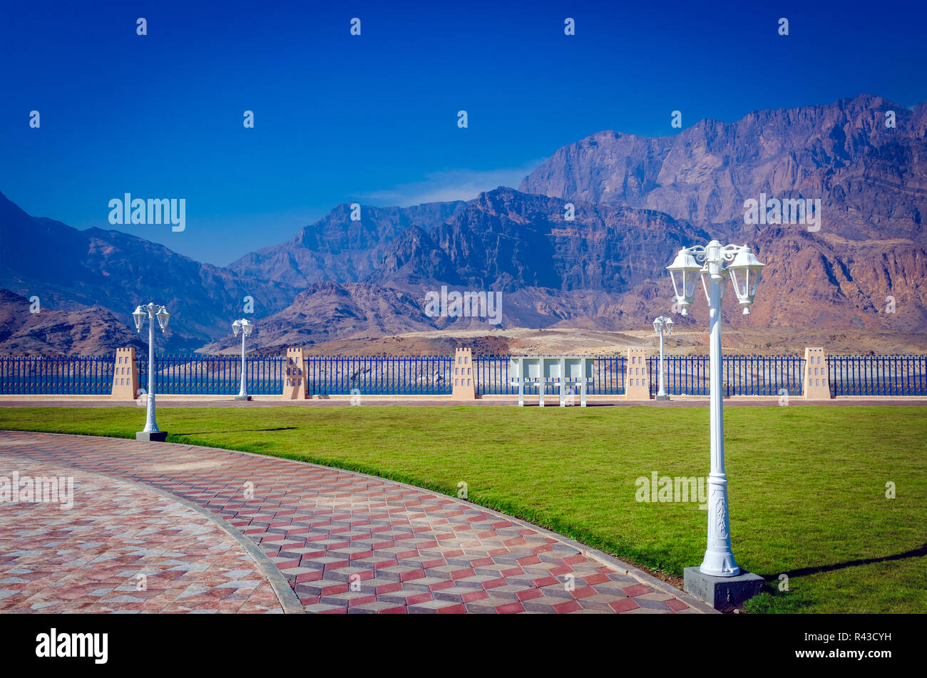 Traditional white lampposts in a park with a beautiful mountain scenery as backdrop. From Muscat, Oman. Stock Photo