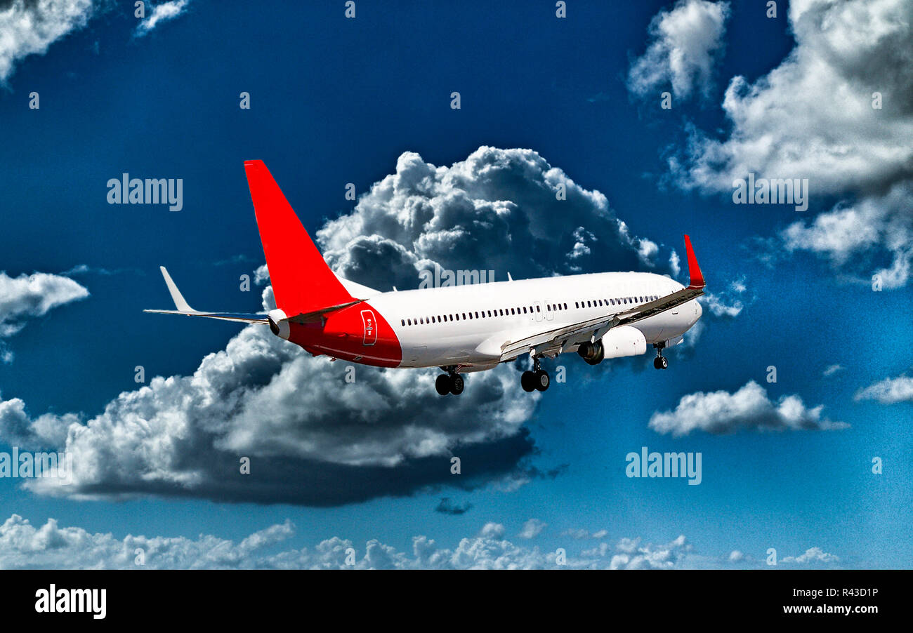 A passenger jet aircraft flyng in a vibrant blue sky, with well developed bright white coloured cumulonimbus clouds, closeup view. Stock Photo