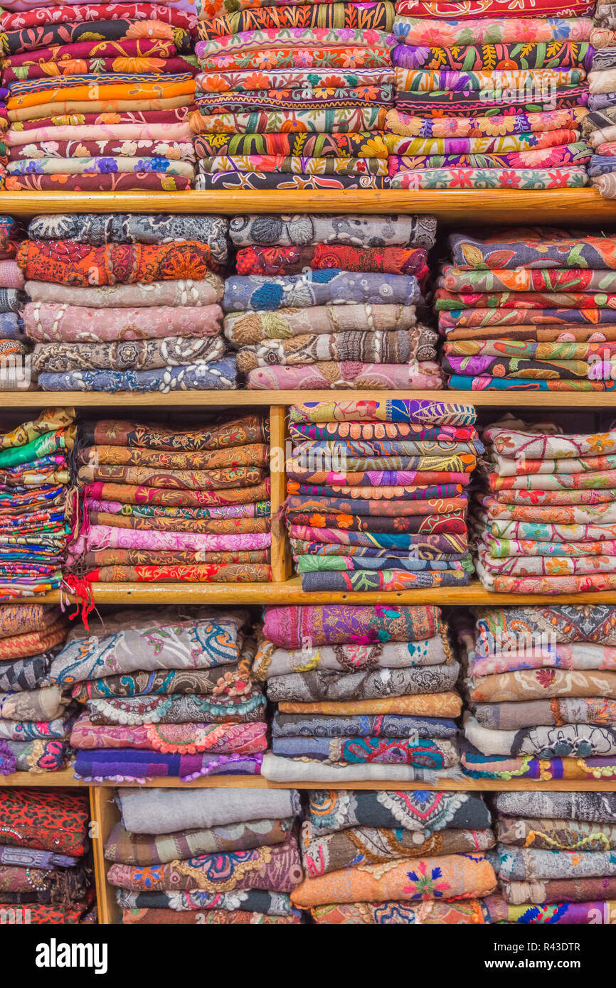 Colorful scarfs displayed neatly folded on shelves, ready for sale in a bazaar. Stock Photo