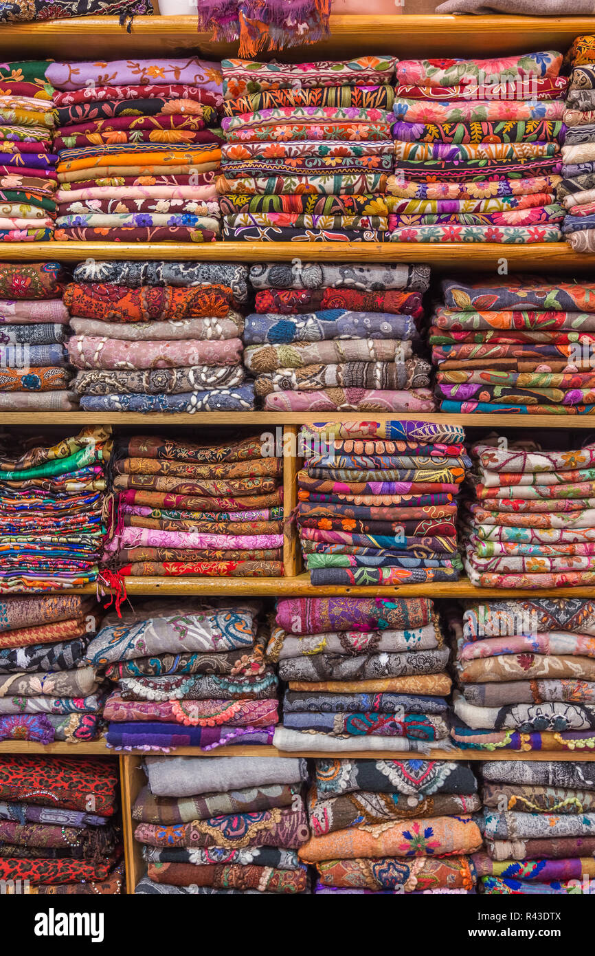 Colorful scarfs displayed neatly folded on shelves, ready for sale in a bazaar. Stock Photo