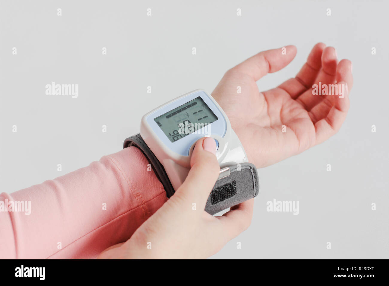 Tonometer device for measuring blood pressure on woman's hand on gray ...