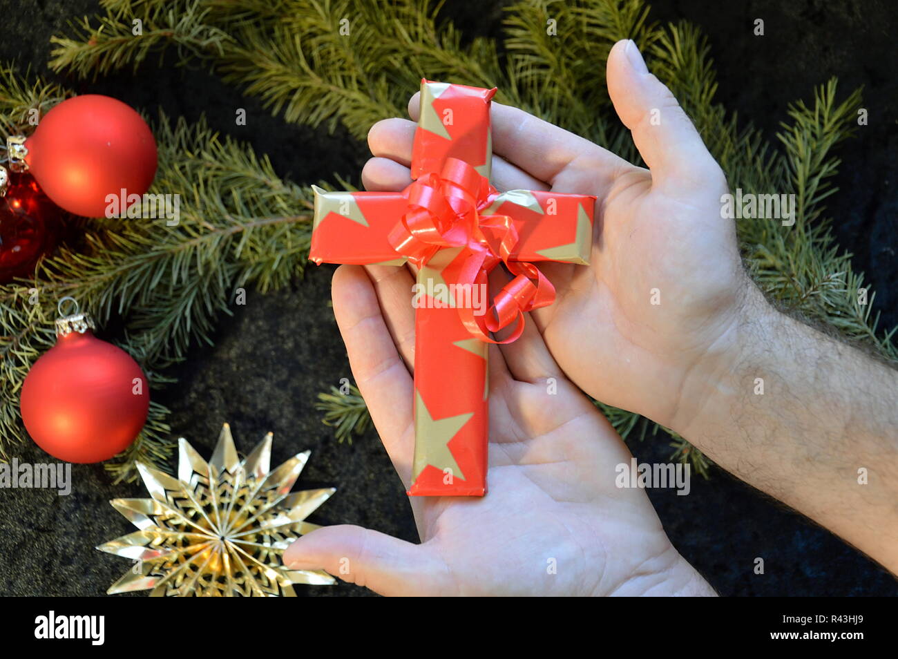 hands give away a boxed in gift paper cross on christmas Stock Photo