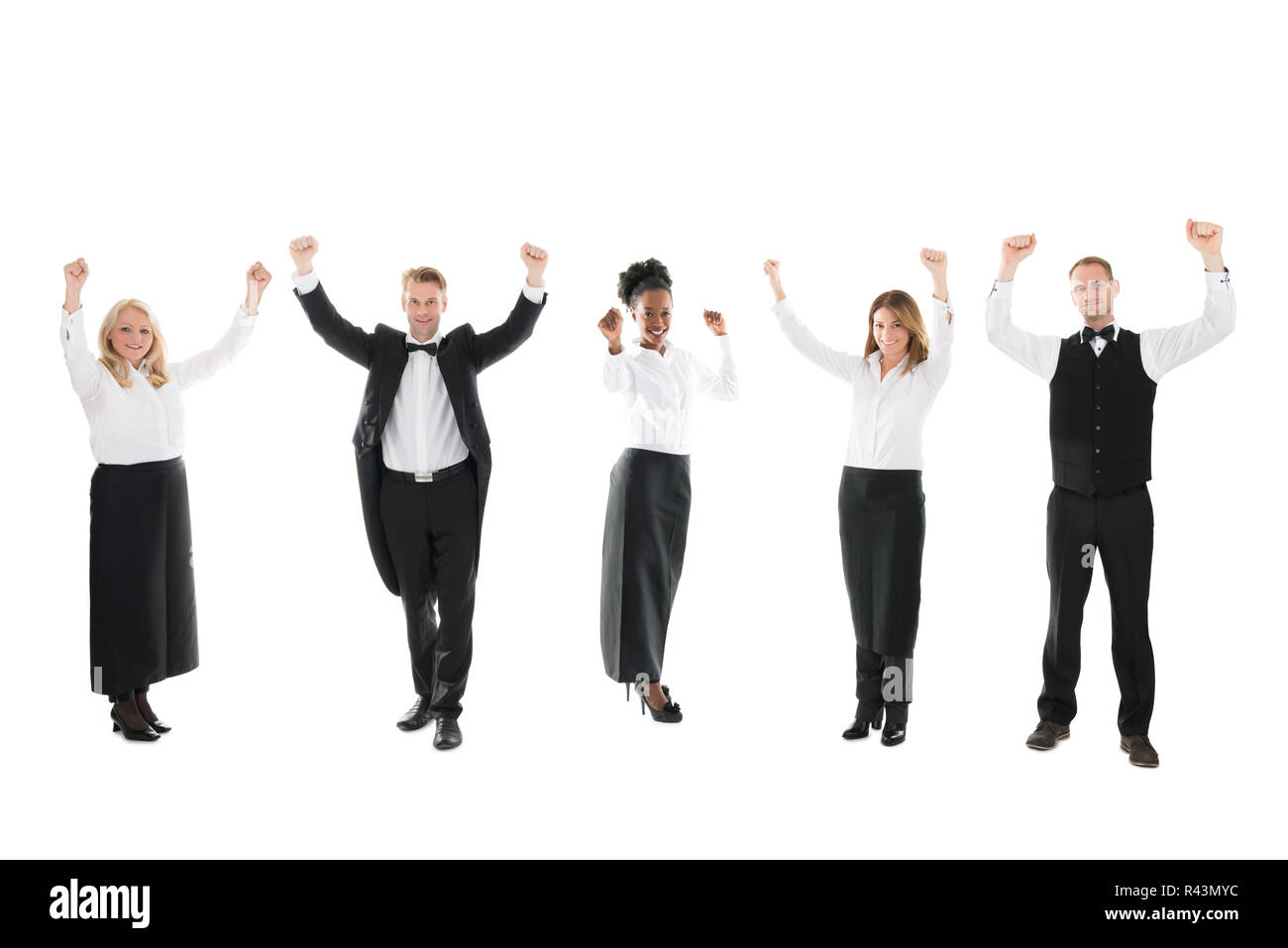 Happy Waiter And Waitresses Standing With Arms Raised Stock Photo