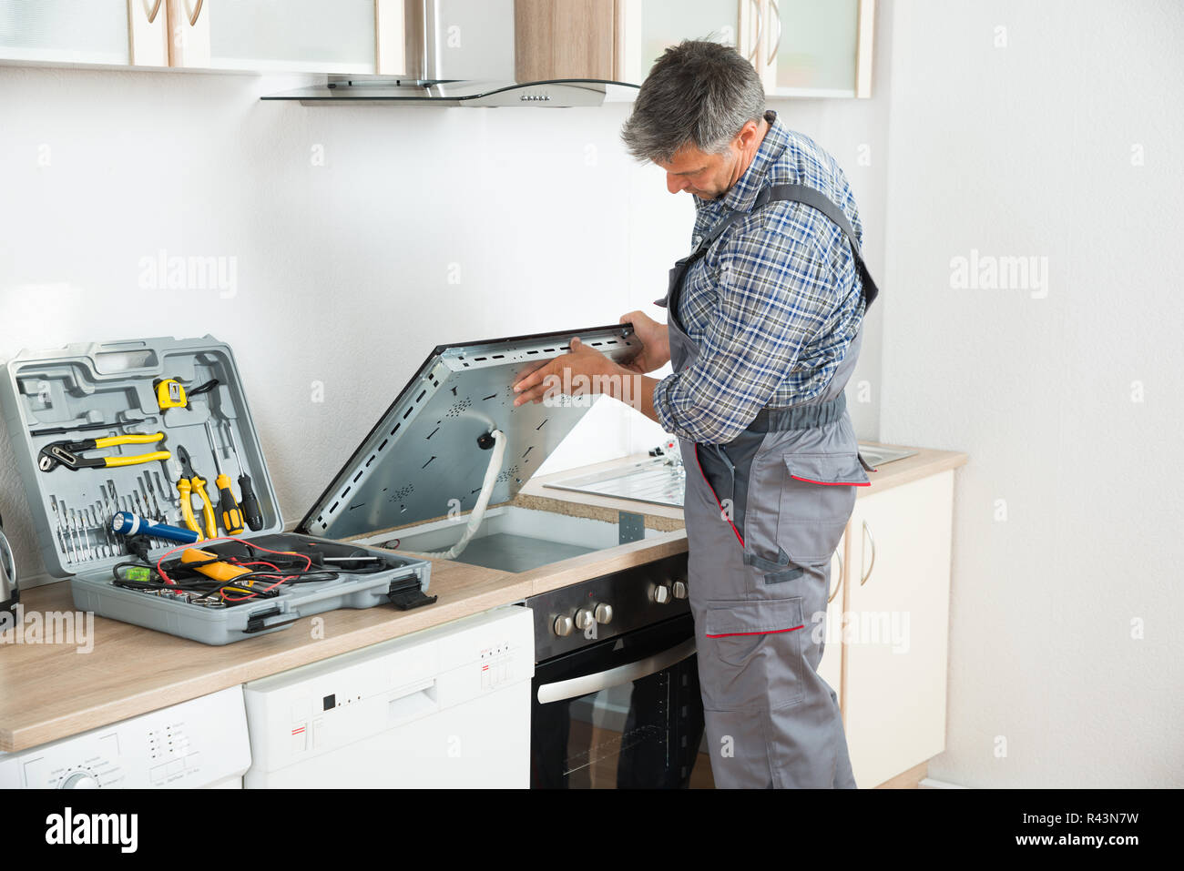 Repairman Examining Stove In Kitchen Stock Photo Alamy