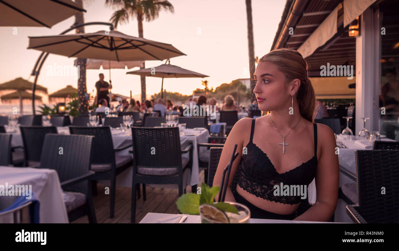 A young woman in a outside dining area of a restaurant in Marbella, Spain. Stock Photo