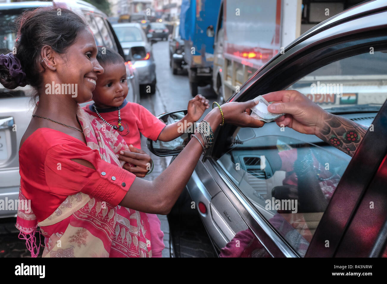 A woman beggar in Colaba area, Mumbai, India, happy to receive a 100 Rupee note from a foreigner Stock Photo