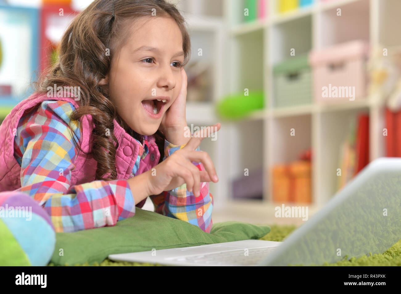 Cute girl using laptop while lying on green floor Stock Photo - Alamy