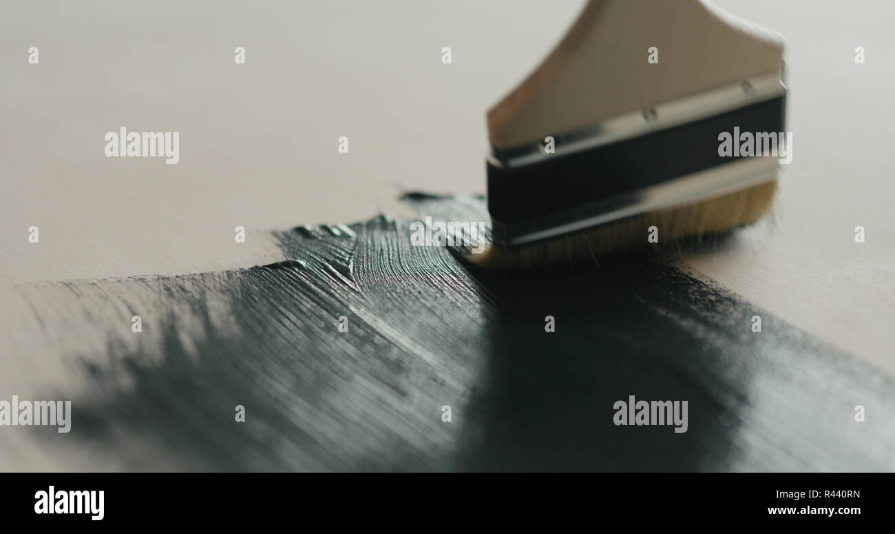Brush painting plywood with black paint Stock Photo Alamy
