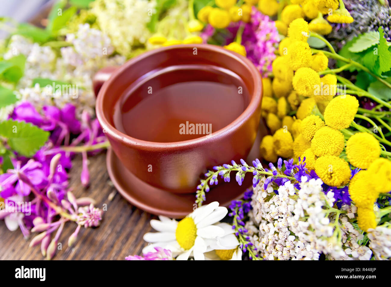 Tea from wild flowers in clay cup on board Stock Photo