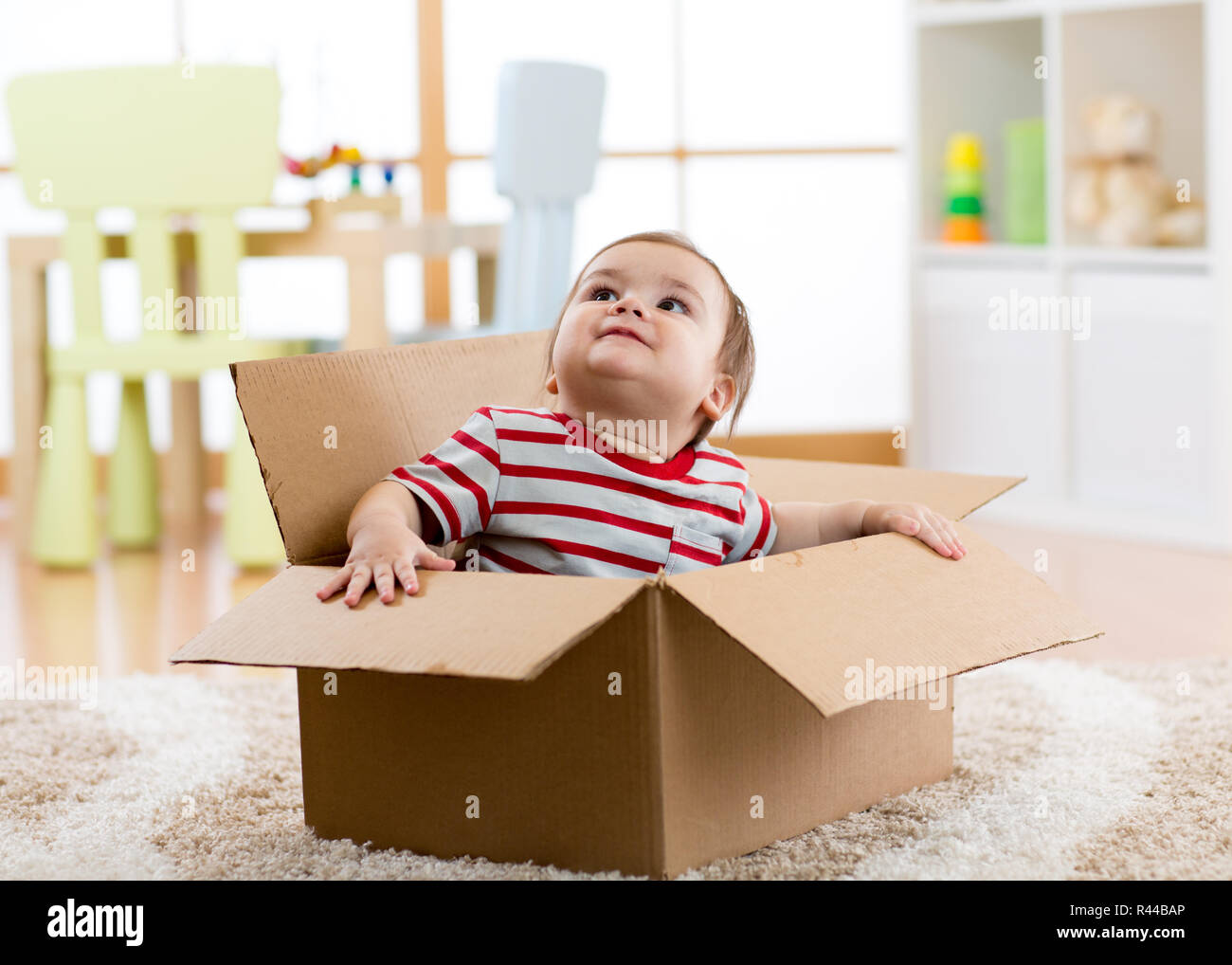 cute little baby infant boy sitting inside cardboard box, moving out concept Stock Photo