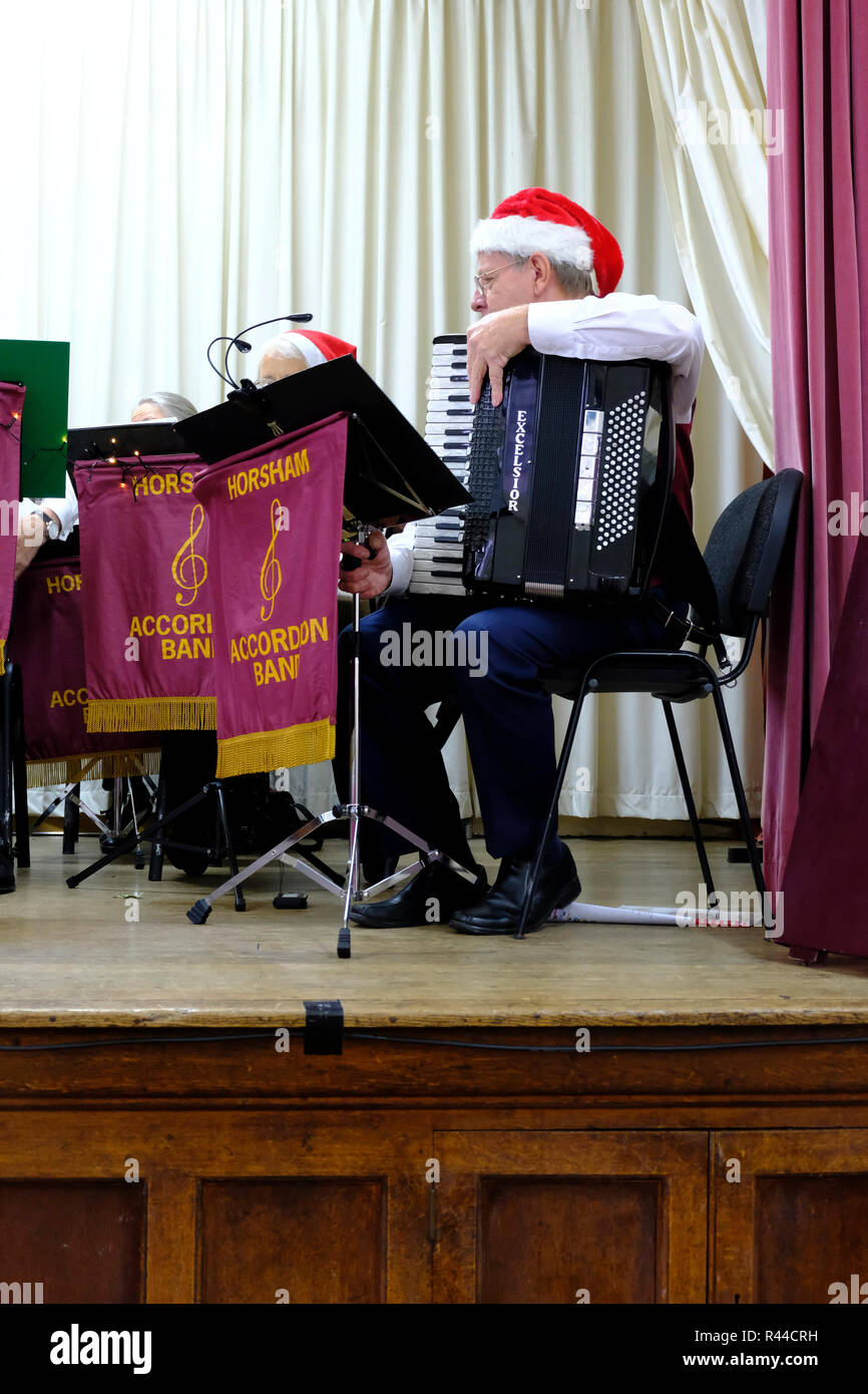 Horsham Accordion Band. Male musician wearing Santa Hat setting up his accordion on stage prior to performance Stock Photo