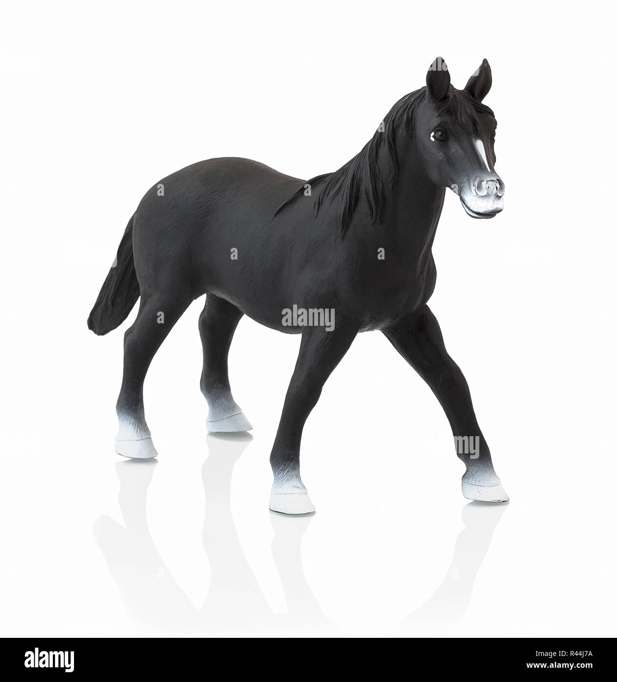 Black horse toy isolated on white background with shadow reflection. Children´s small plastic black horse on white backdrop. Miniature plastic model o Stock Photo