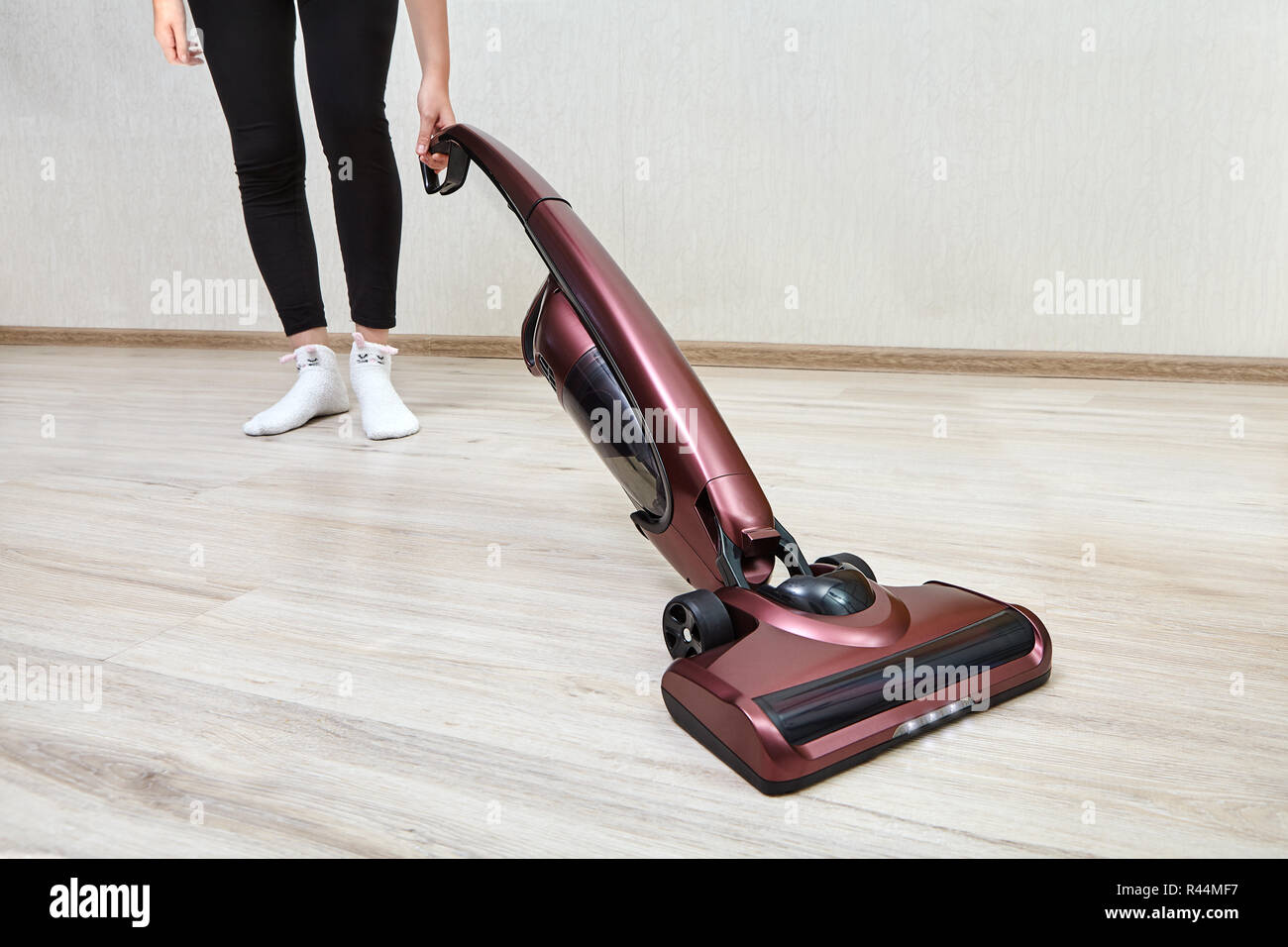 Cleaning Lady In Black Leggings Cleans Dust In An Empty Room Using A Cordless Handheld Vacuum 