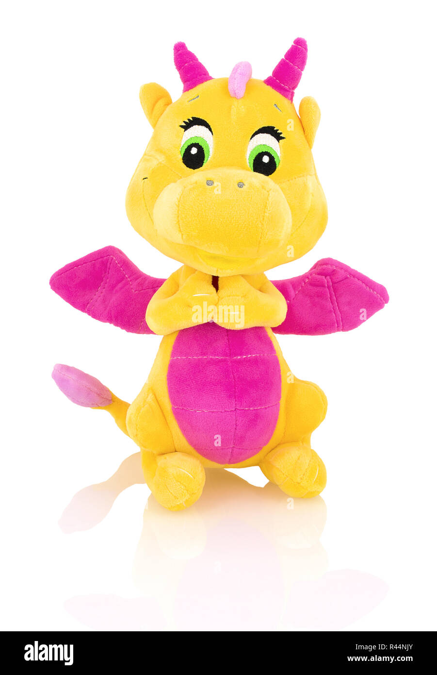 Dragon plushie doll isolated on white background with shadow reflection. Yellow stuffed dragon with purple horns and wings isolated on white backdrop. Stock Photo