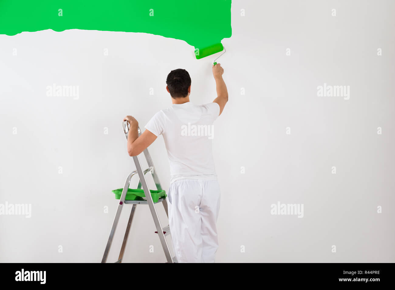 Man Painting Wall With Green Paint Roller Stock Photo - Alamy