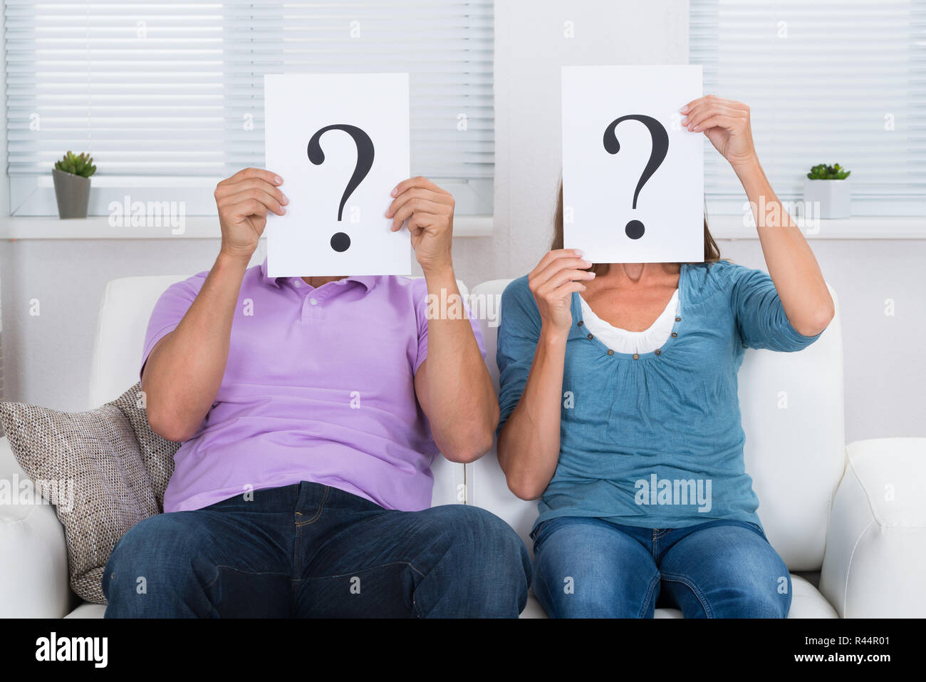 Couple Hiding Face With Question Mark Sign Stock Photo
