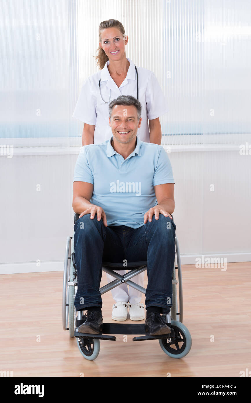 Doctor Carrying Patient On Wheelchair Stock Photo Alamy