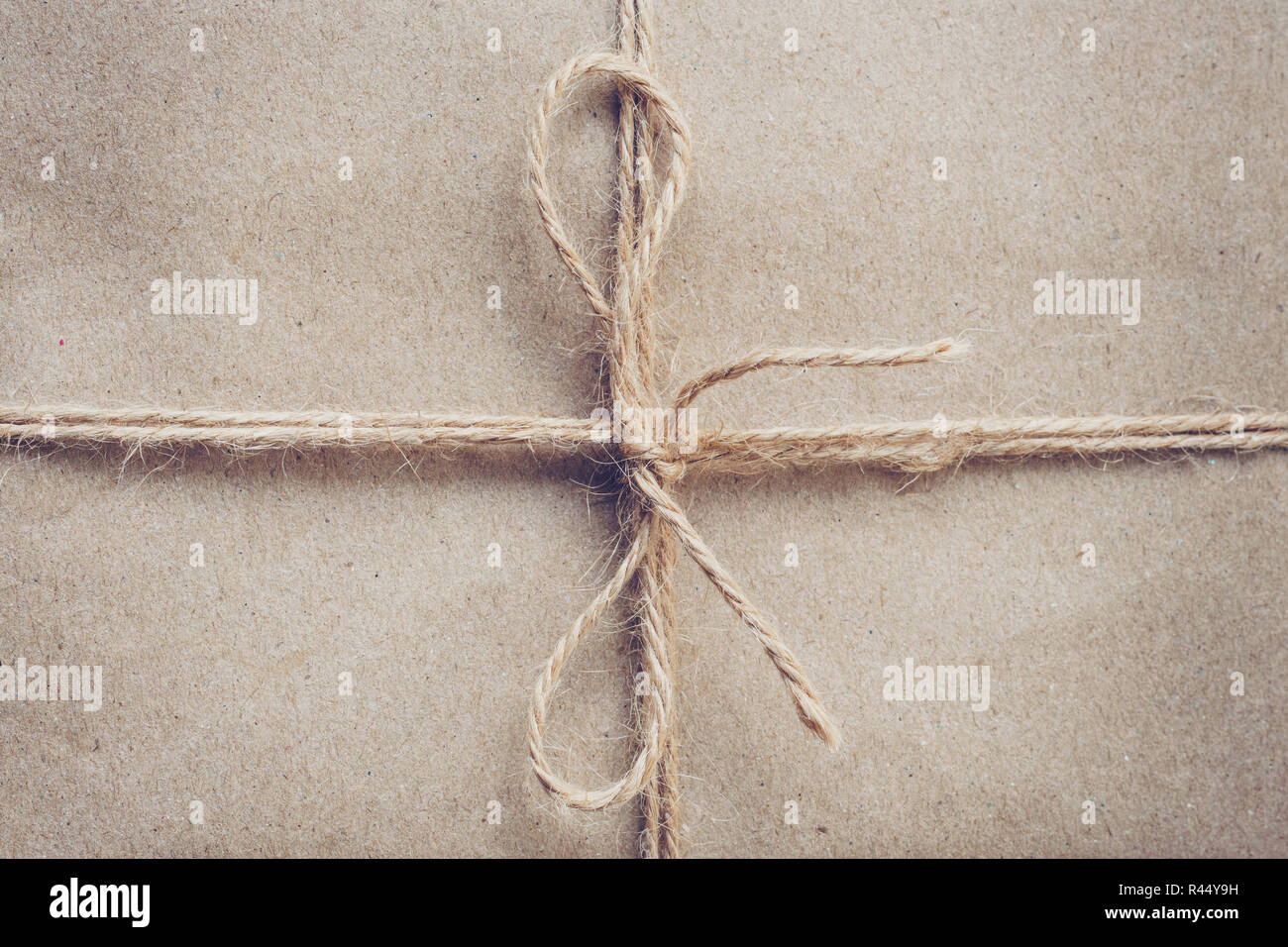 String or twine tied in a bow on brown kraft paper texture. Stock Photo
