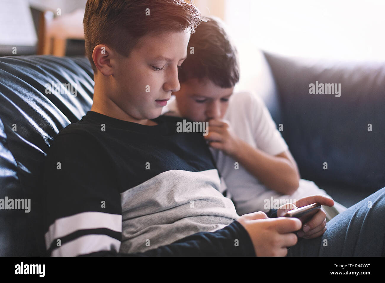 Little boys using smartphone on sofa at home Stock Photo