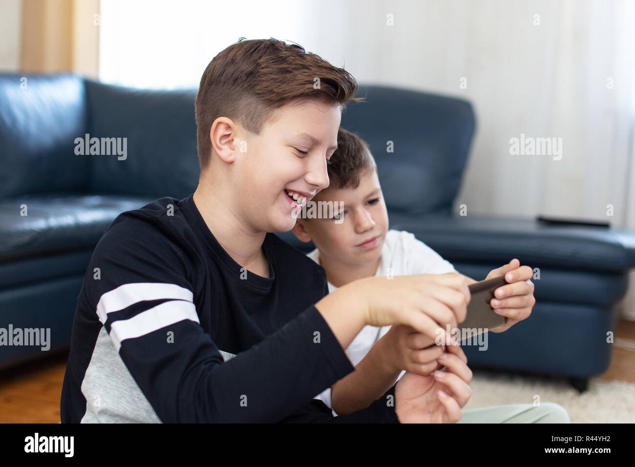 Happy little caucasian boys using smartphone at home Stock Photo