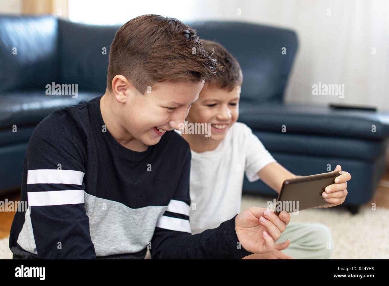 Happy boys using smartphone at home and laughing at home Stock Photo