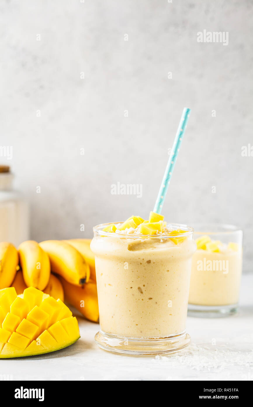 Mango banana smoothie with coconut in a jar. Plant based food concept. Stock Photo