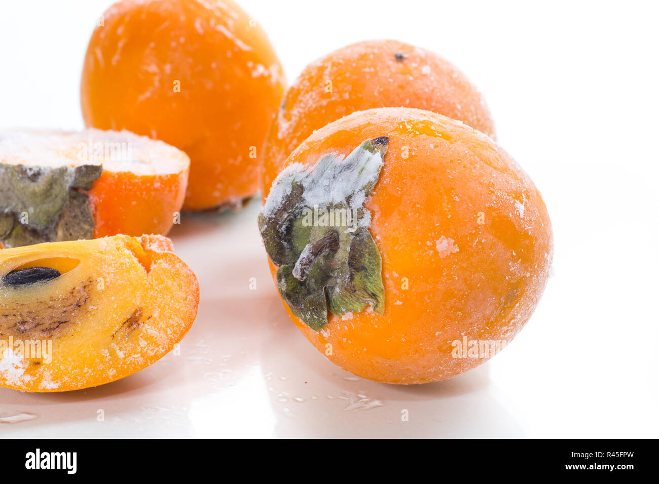 frozen ripe persimmon in ice isolated on white Stock Photo - Alamy