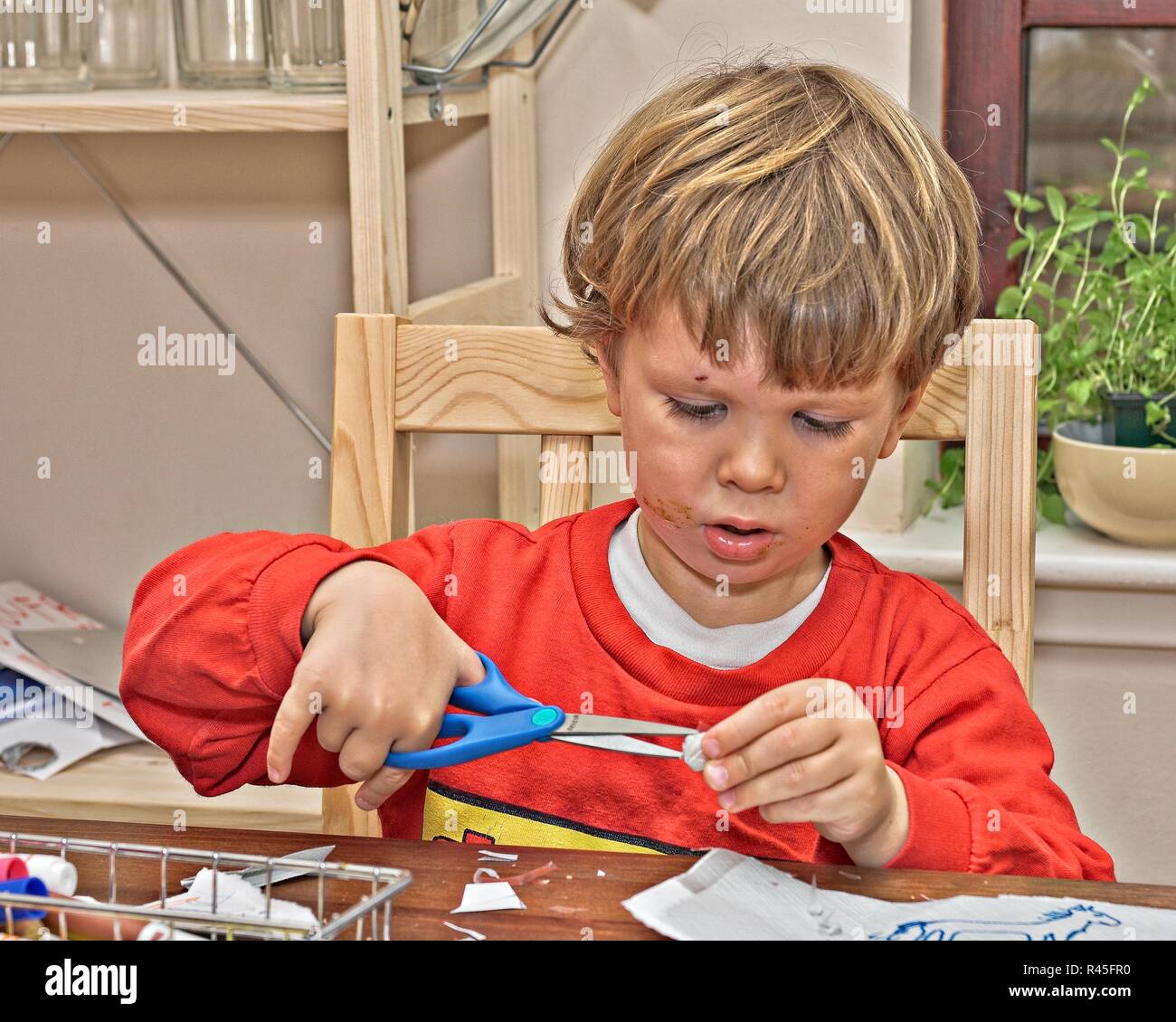 Boy Using Paper Young boy playing with paper and scissors Stock Photo - Alamy