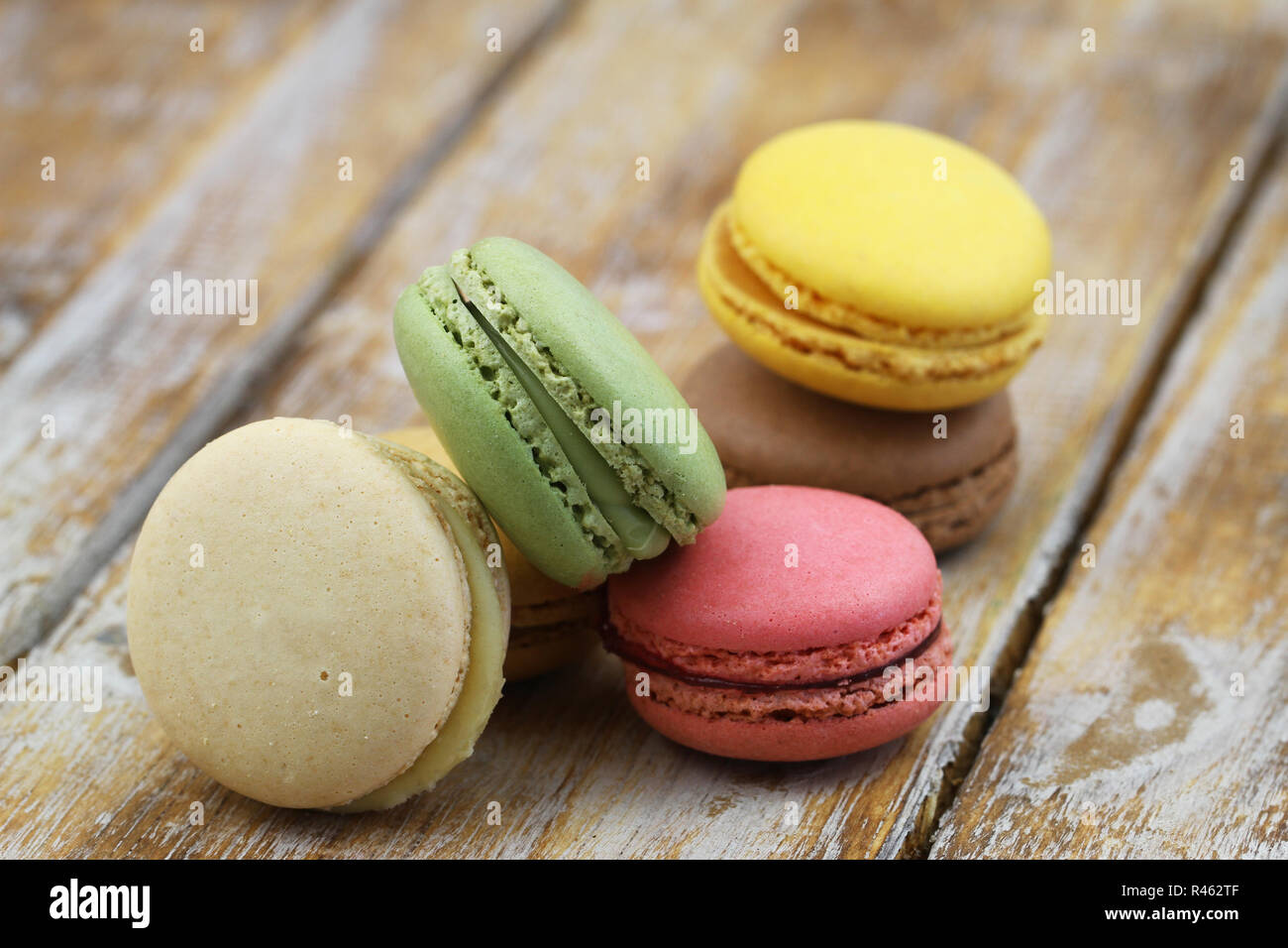 Colorful crunchy macaroons stacked up on rustic wooden surface with copy space Stock Photo