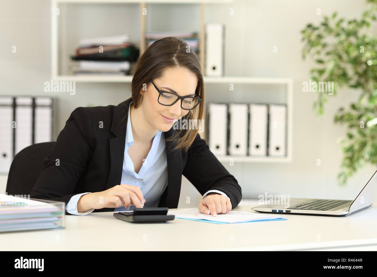 Office worker wearing eyeglasses doing accounting on a desk Stock Photo