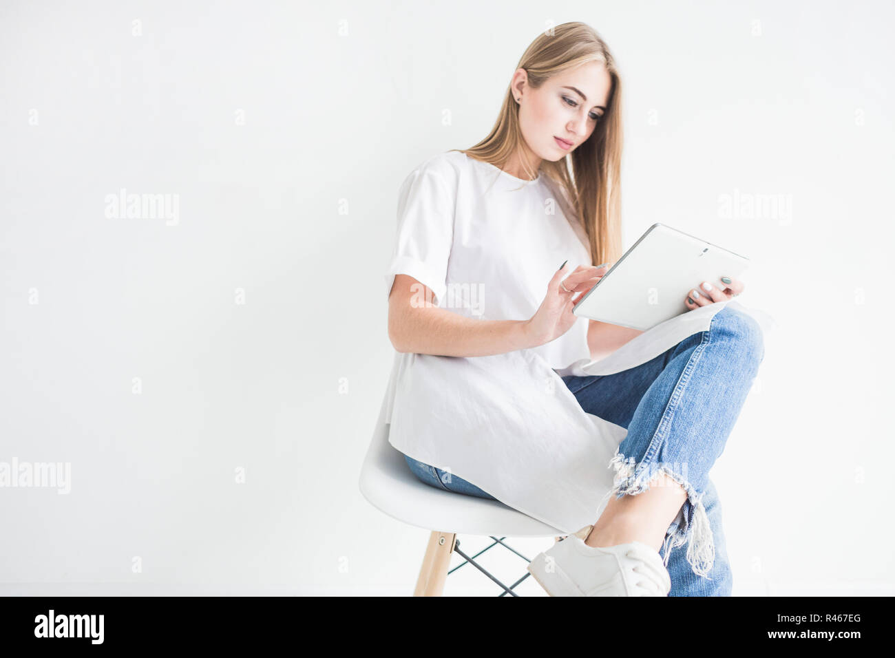 Portrait of a young stylish blonde girl in a white T-shirt and blue ...