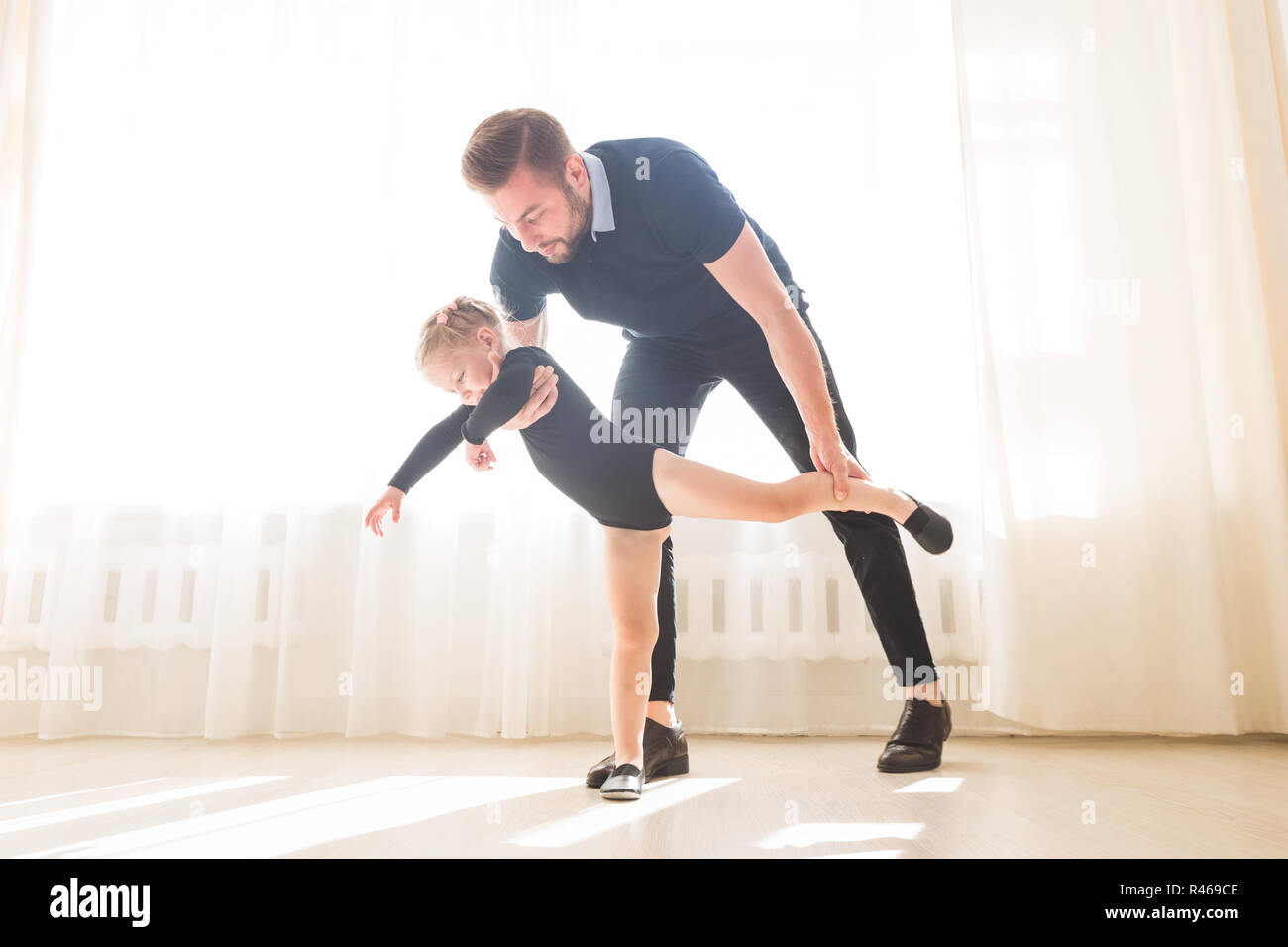 Father teaches to dance his cute little daughter. Stock Photo