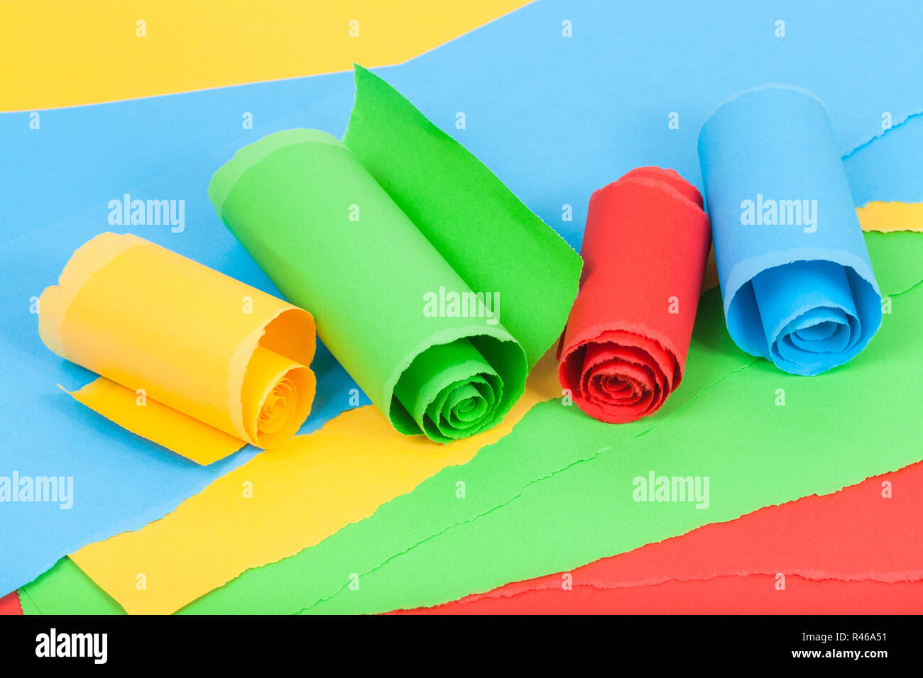 rolled colour paper on sheets of torn paper Stock Photo Alamy