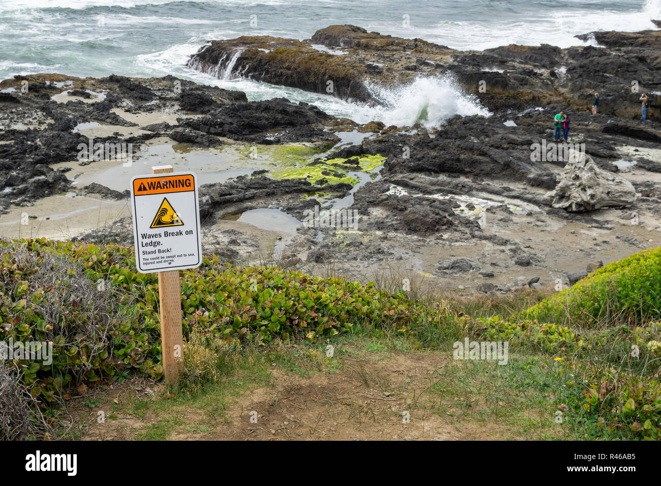 Waves break on ledge warning sign at Cape Perpertua Scenic Area, Oregon Coast, USA. Stock Photo