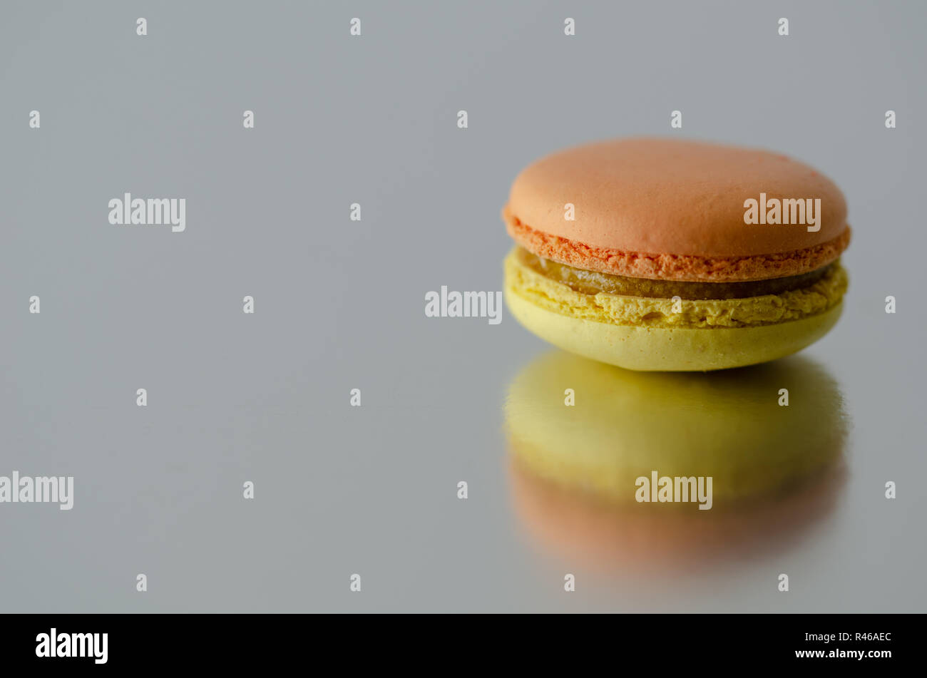 Two colored macarons are reflected on the table. Stock Photo