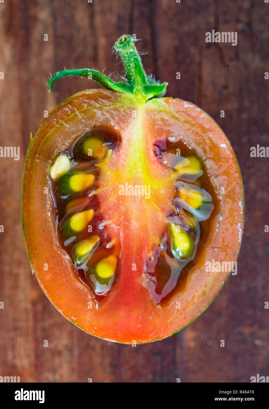 half,red tomato cut open on rustic wooden table Stock Photo