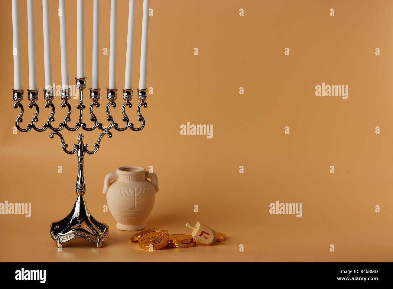 Image of jewish holiday Hanukkah with menorah and wooden dreidel, jug, coins Stock Photo