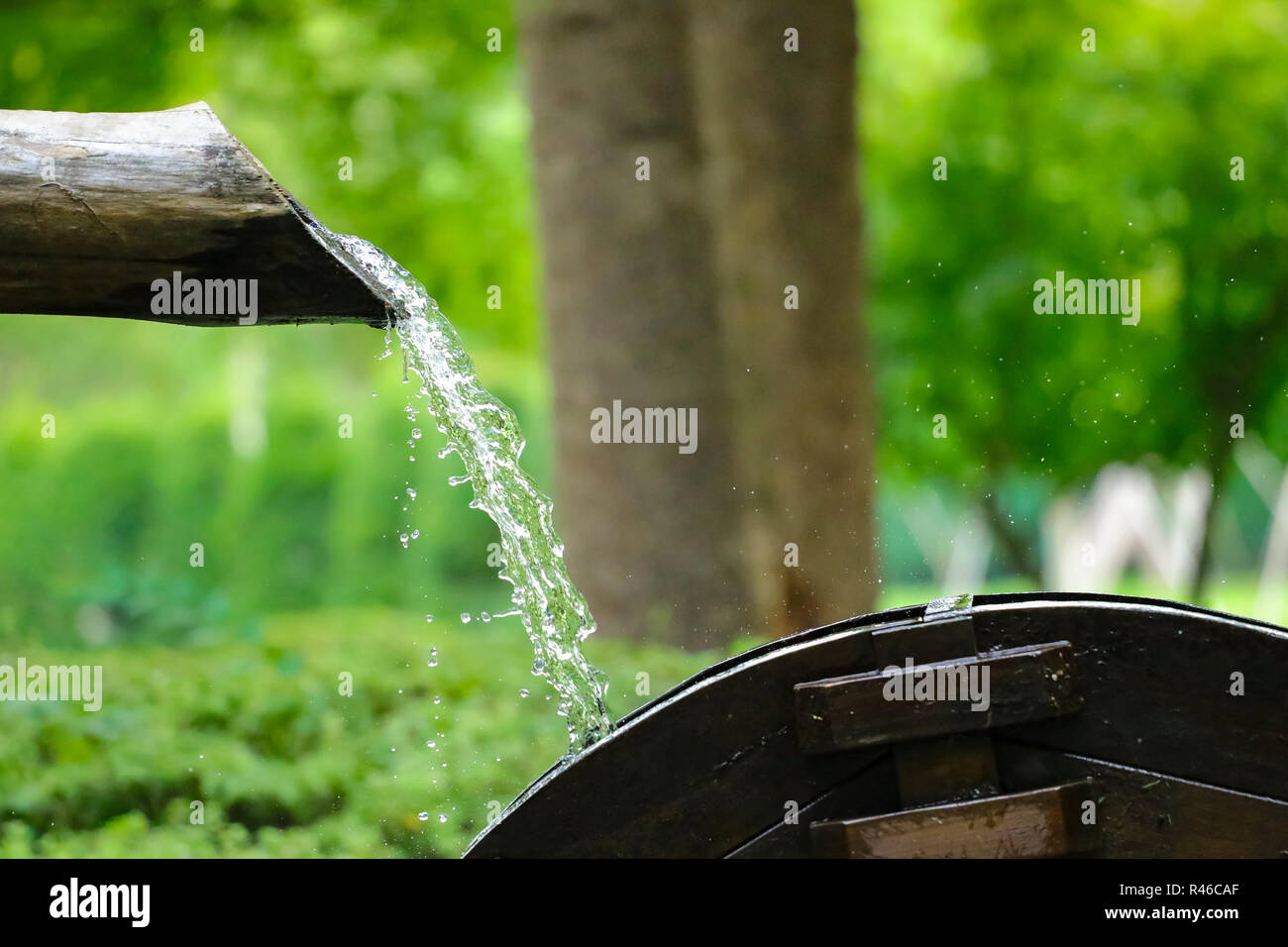 water flows from a wooden pipe or water gushing out of the pipe close up Stock Photo