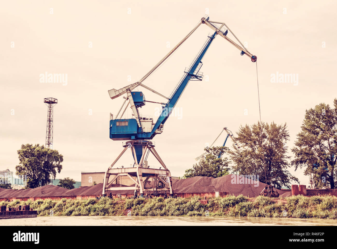 Blue crane in cargo port translating coal. Industrial scene. Red photo filter. Stock Photo