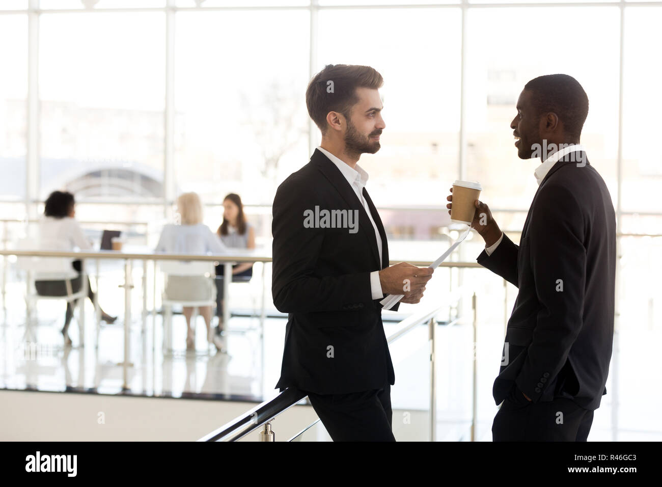 Diverse millennial businessmen colleagues talking standing in mo Stock Photo